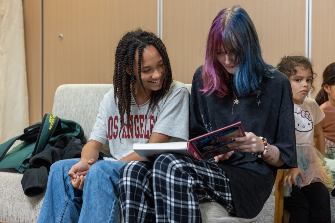 Two older students share a book on a couch.